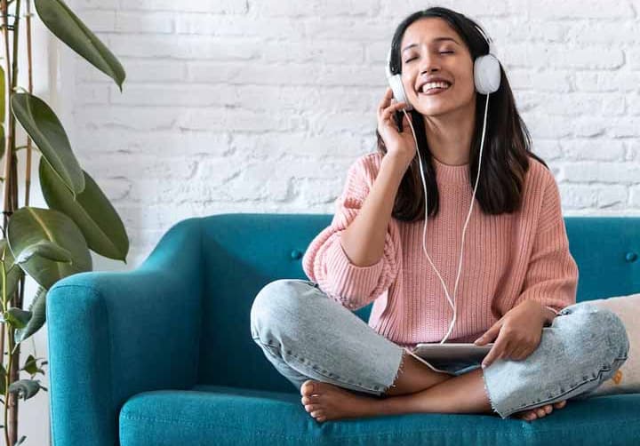 A young lady listening to music on the couch.